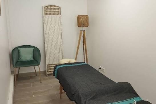 Pièce au calme avec fauteuil vert et lampe en bois.