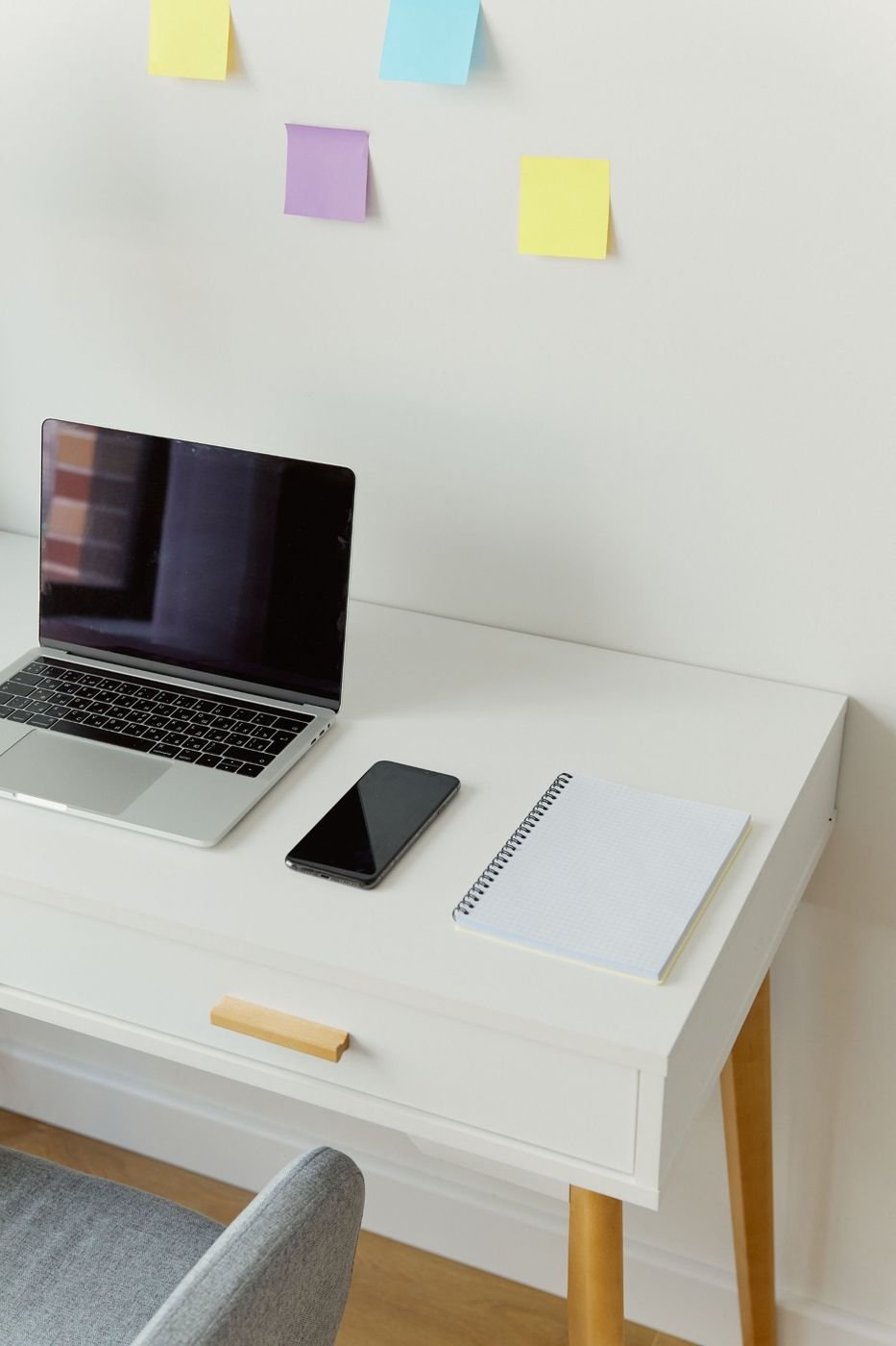 Ordinateur portable, téléphone et carnet sur un bureau blanc.