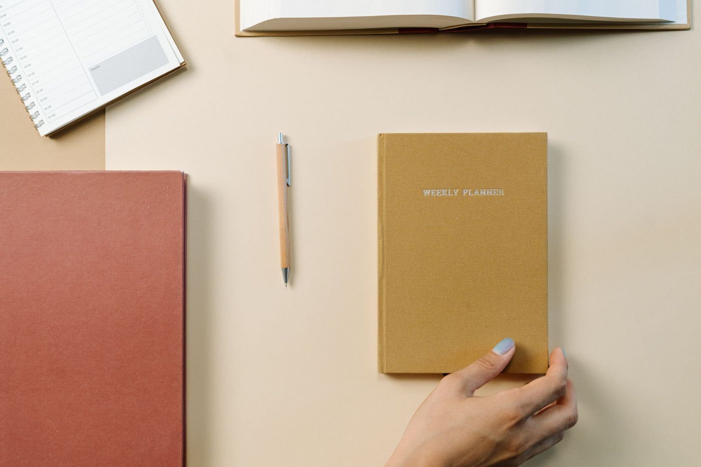 Carnets, agenda et stylo disposés sur un bureau beige.